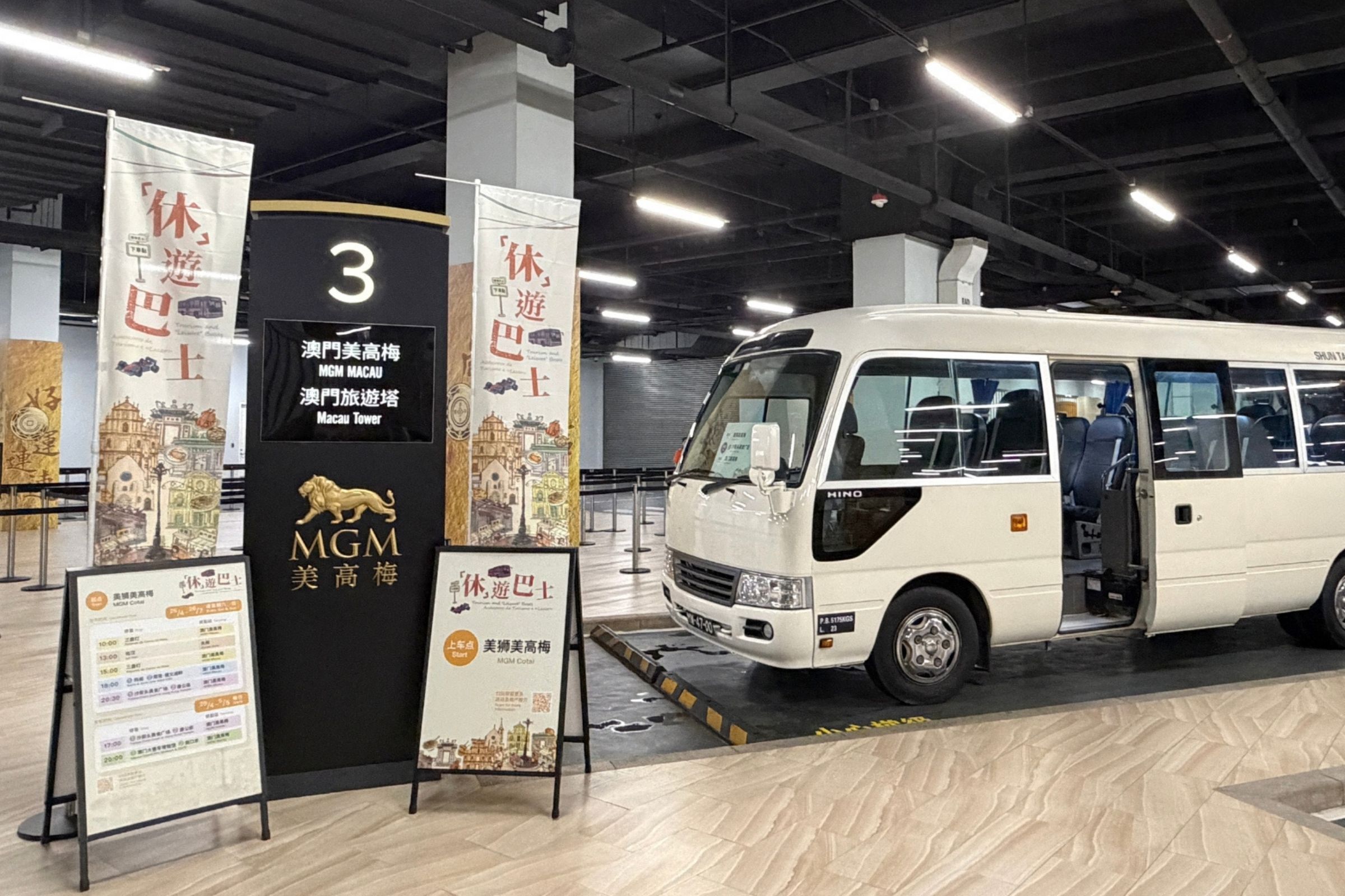 美高梅「『休』遊巴士．社區探趣」免費穿梭巴士停泊於美獅美高梅3號上車點，旁設活動宣傳易拉架及路線資訊。