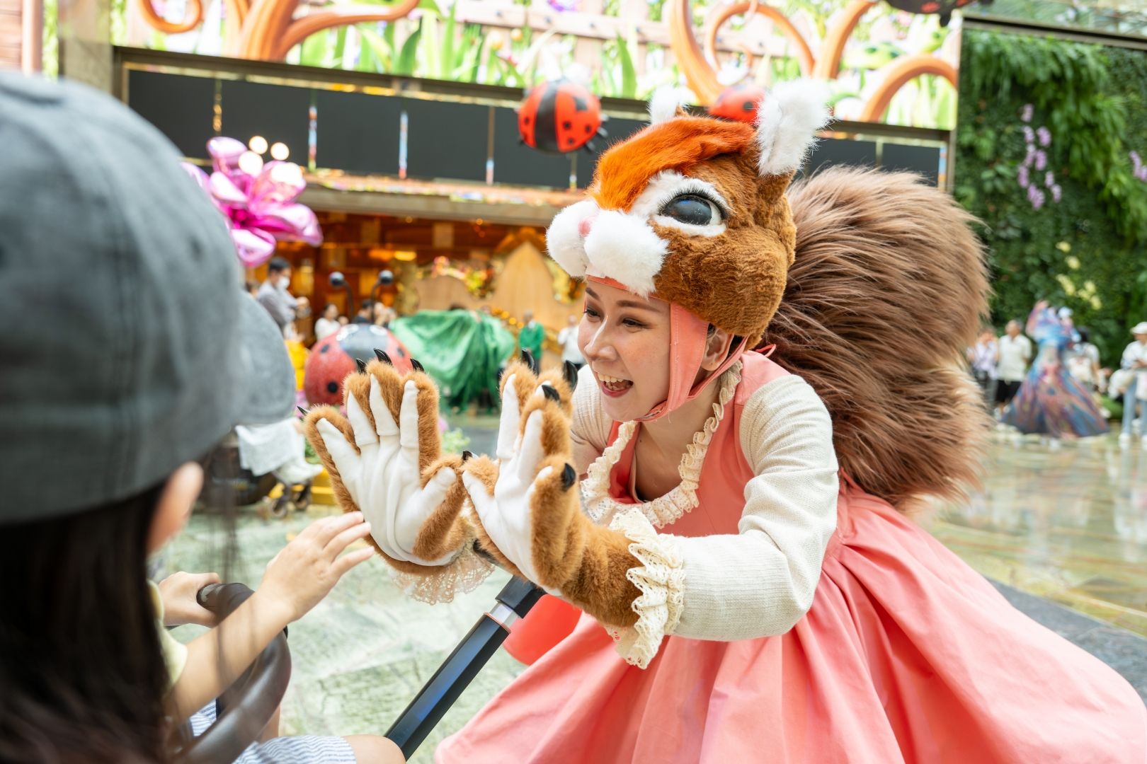 A Garden Wonderland performer in a woodland-inspired costume interacts with a child at The Spectacle in MGM COTAI, creating a fun and immersive family entertainment experience.